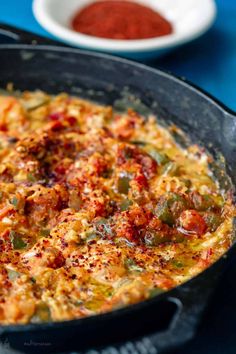 an omelet with tomatoes and peppers in a black pan on a blue table