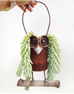 an owl made out of branches and leaves is hanging on a branch with its eyes open