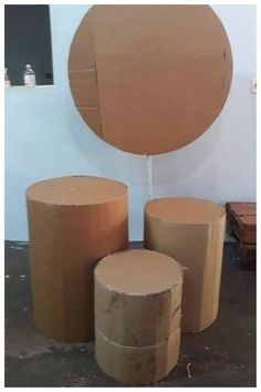 three round cardboard boxes sitting next to each other on top of a cement floor with a circular mirror in the background