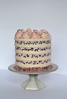 a white cake with pink frosting and leopard print on the top is sitting on a plate