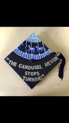 a graduation cap with the words the carousel never stops turning on it and an ornament hanging from the top