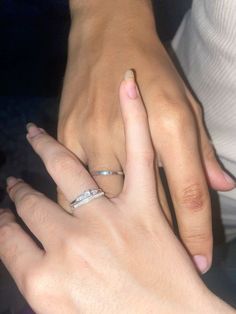 two people holding hands with wedding rings on their fingers and one wearing a diamond ring