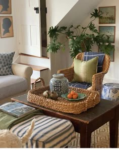 a living room filled with furniture next to a stair case and potted plant on top of a coffee table