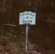 a white sign that says entering salem on it's side in front of some trees