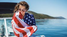 a woman with an american flag draped over her head on a boat in the water