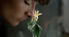 a woman smelling a flower with her eyes closed