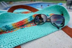 a pair of sunglasses laying on top of a towel next to a pool