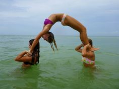 two women are in the water doing handstands