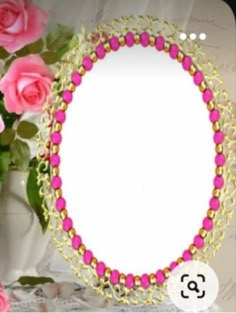 a pink beaded necklace with a white tag on it next to some pink roses