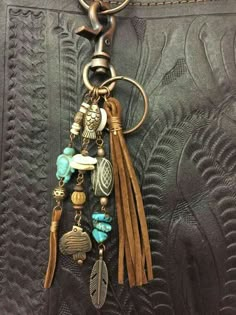 a keychain with charms hanging from it's side on a black leather background