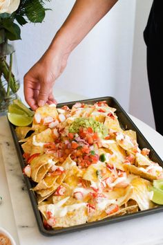 a person reaching for nachos on a tray