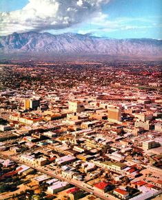 an aerial view of a large city with mountains in the backgrouund and clouds in the sky