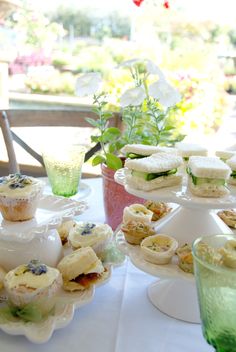 three tiered trays filled with different types of pastries on a table next to tea cups and saucers