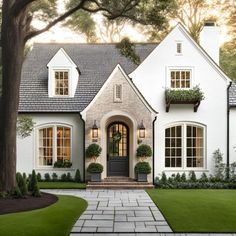 a white house with lots of windows and plants on the front door is featured in this postcard