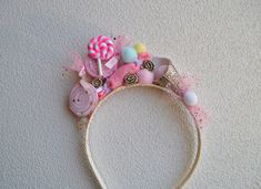 a pink headband with candy and candies on the top is laying against a white wall