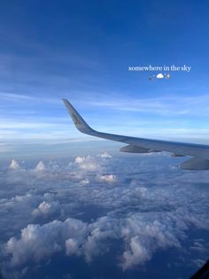 an airplane wing flying above the clouds and blue sky with some somewhere in the sky written on it