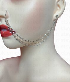 a mannequin head wearing a silver chain choker with red lips and piercings