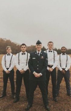 a group of men standing next to each other on top of a grass covered field