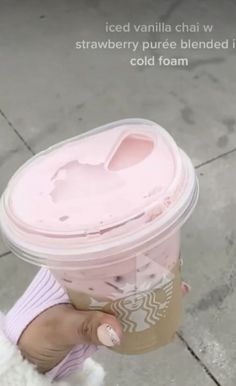 a person holding a cup with pink liquid in it and the words iced vanilla chat w strawberry puree blended into cold foam