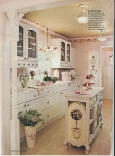 an old fashioned kitchen with white cabinets and flowers in vases on the counter top