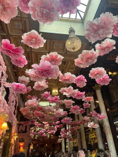 pink paper flowers hanging from the ceiling in a restaurant with chandelier and chandeliers