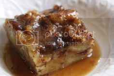 a piece of bread pudding on a white plate with caramel sauce in the middle