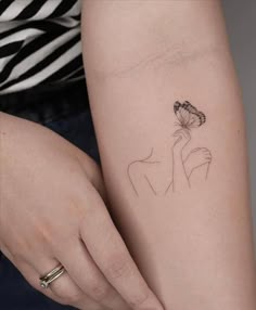 a woman's arm with a small flower tattoo on the left side of her right arm