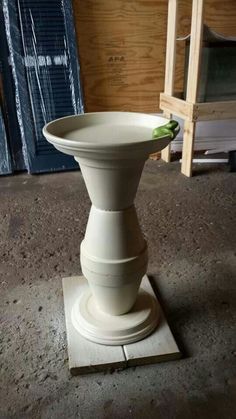 a white vase sitting on top of a wooden stand