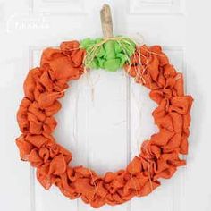 an orange and green wreath hangs on the front door to give it a festive touch