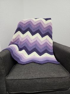 a crocheted blanket sitting on top of a couch next to a gray chair