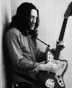 a man with long hair holding an electric guitar