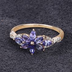 a gold ring with purple and white stones on it, sitting on a black surface