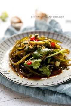 a white plate topped with vegetables covered in sauce on top of a blue and white cloth