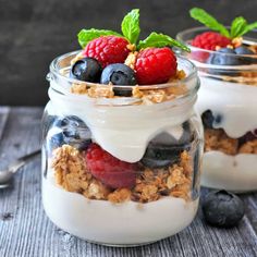 yogurt parfait with berries and granola in glass jars on wooden table