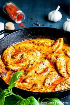 a pan filled with chicken and sauce next to garlic