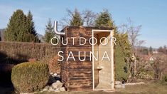 an outdoor sauna with the words out door in front of it and bushes around it