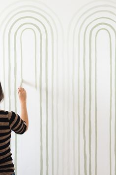 a woman is painting a wall with vertical lines