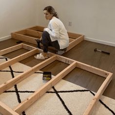 a woman kneeling on the floor working on framing