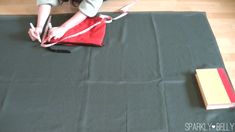 a woman is sitting on the floor with scissors and a red bag in front of her