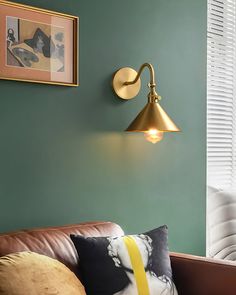 a living room with green walls and a brown leather couch in front of a wall light