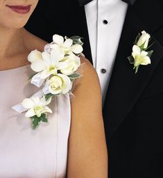 a man in a tuxedo and woman in a dress with flowers on their lapel