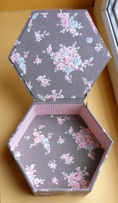 an open box sitting on top of a window sill next to a flowered wall