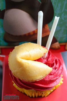 a cupcake with some toothpicks sticking out of it's middle sitting on a red plate