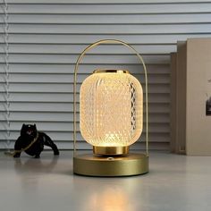 a white lamp sitting on top of a table next to a black cat