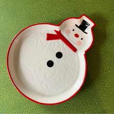 a plate with a snowman design on the front and bottom, sitting on a green surface