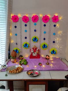 a table topped with plates and bowls filled with food next to a wall covered in paper flowers