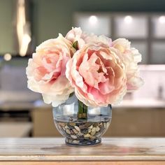 two pink flowers in a glass vase on a table