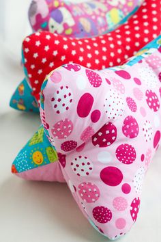 three different colored pillows with polka dots on them, one is pink and the other is red