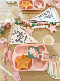 a table topped with pink trays filled with different types of food and decorations on top of a wooden table