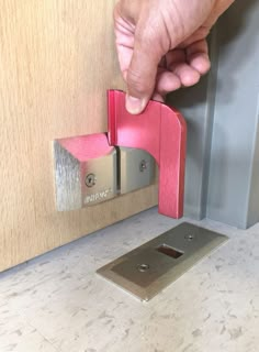 a person opening a door with a pink handle